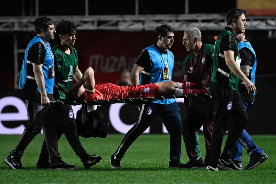Luciano Sanchez, do Argentinos Juniors, é retirado de campo após a grave lesão sofrida em pisão de Marcelo, do Fluminense — Foto: Luis Robayo/AFP