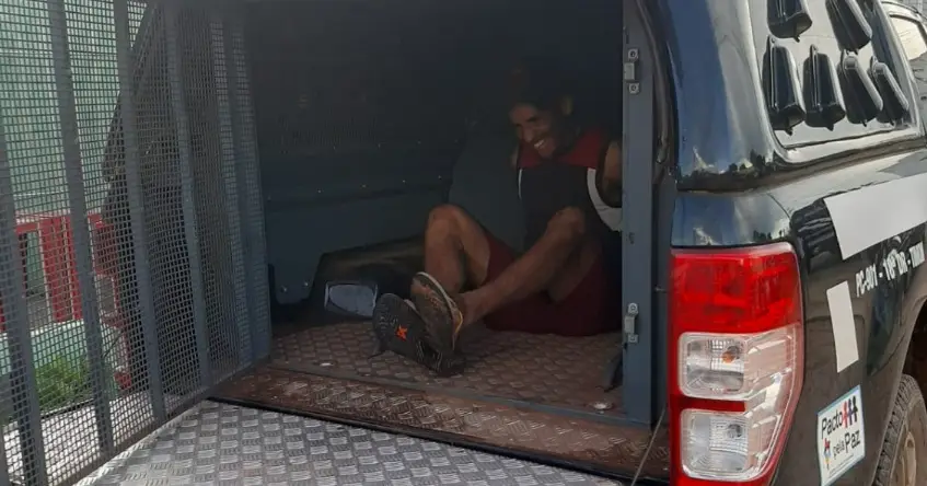O agressor ainda esboça sorriso ao descer da viatura da Polícia Civil